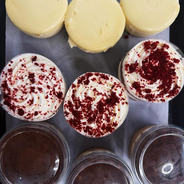 Top-down view of three cheesecakes, three red velvet parfaits, and three chocolate desserts.