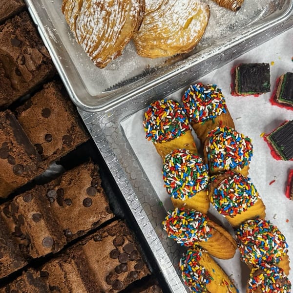 Assortment of Italian pastries including sfogliatelle, rainbow cookies, and chocolate chip brownies.