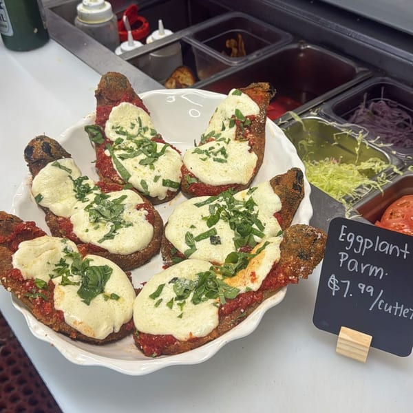 A white platter filled with Gabagool's eggplant parmesan cutlets, topped with melted cheese and basil.